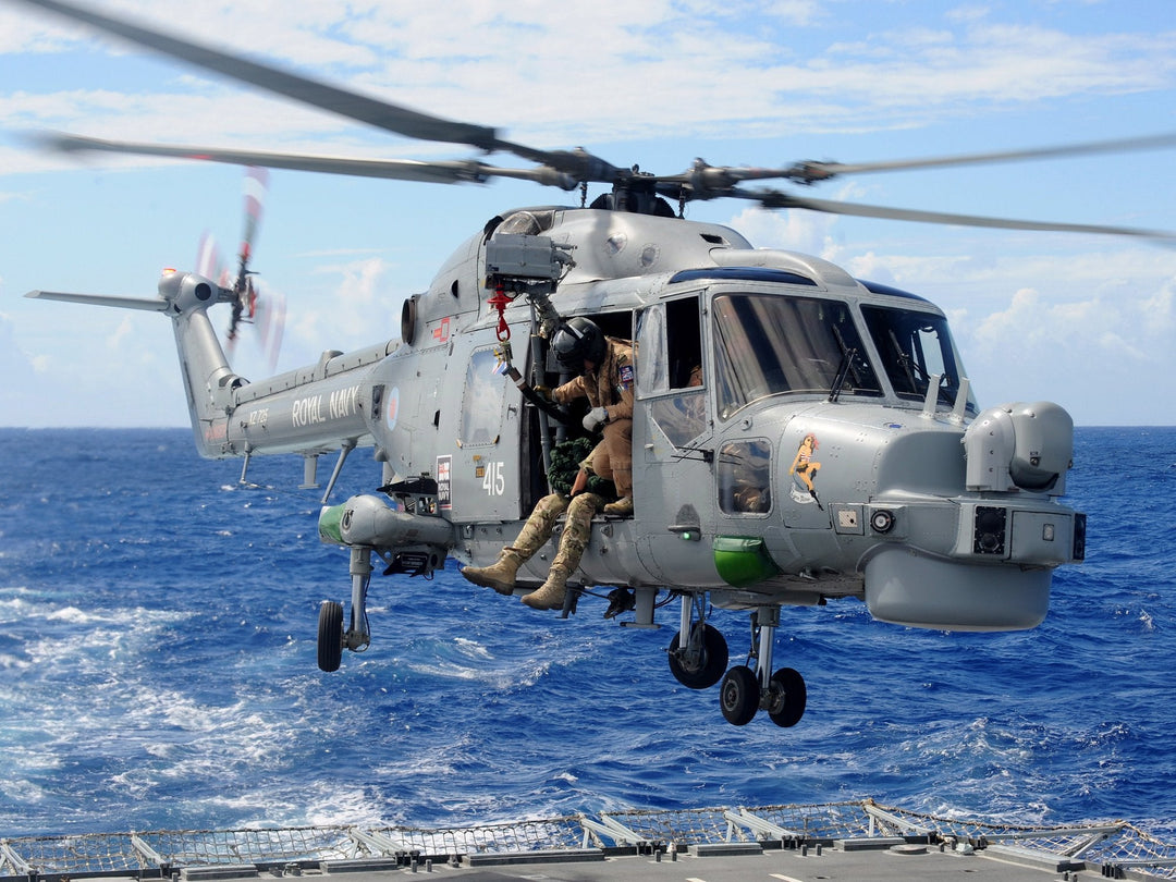 A Royal Navy Lynx, call sign Black Knight, hovers just above the flight deck of HMS Monmouth as Royal Marines and sailors of the boarding team practise fast roping, 3 June 2011